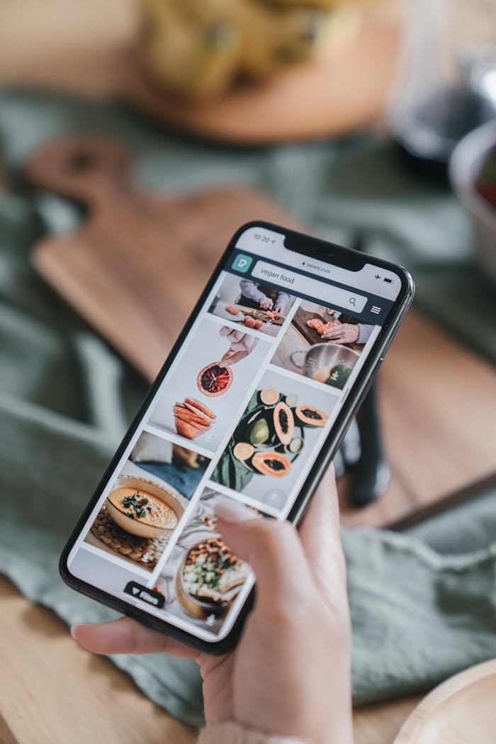 gallery-1 Close-up of a hand holding a smartphone browsing food recipe images.