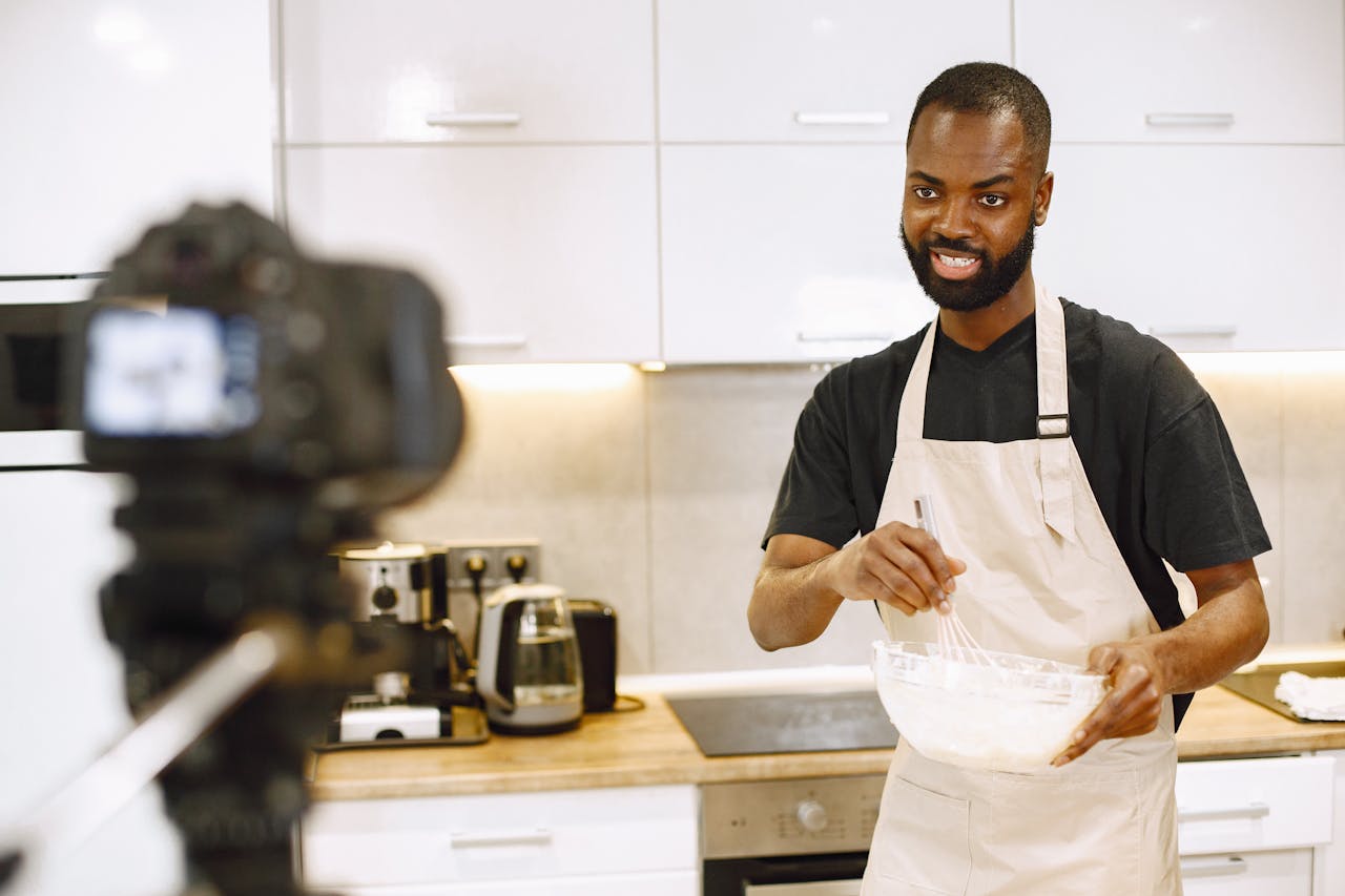 about-01 African American man whisking ingredients for a cooking video in a modern kitchen.