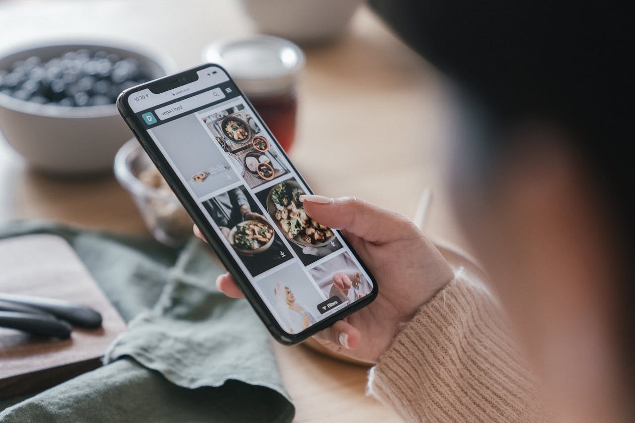 why-choose-us Close-up of a hand holding a smartphone browsing food recipes. Cozy kitchen setting.